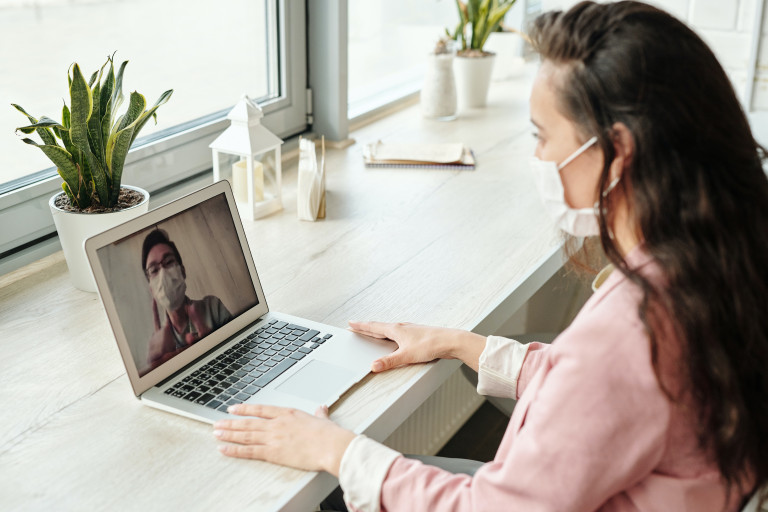 Frau mit Maske an Laptop